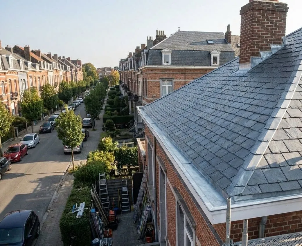 Après : toiture en ardoises naturelles neuves, arêtiers et corniche en zinc sur une maison de Woluwe